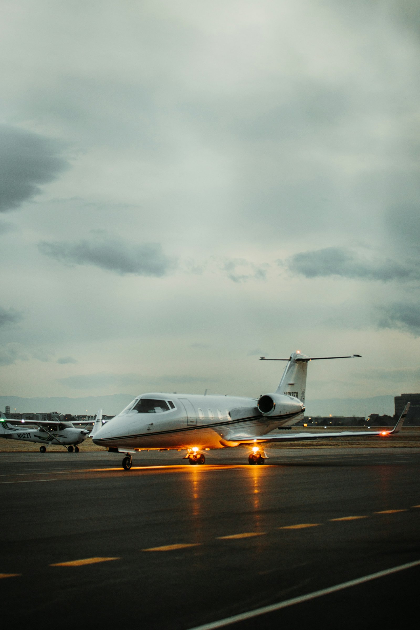 Illustrative private jet on a wet apron at dusk; backdrop to the services aircraft inquiry form